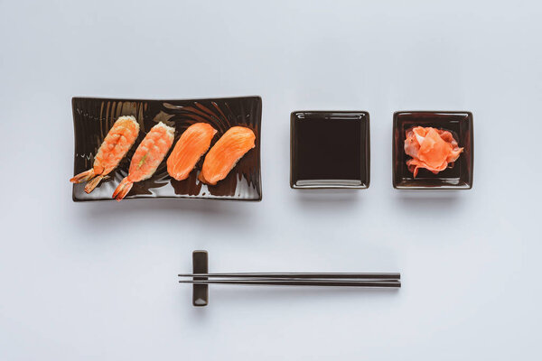 top view of gourmet sushi with salmon and shrimp, ginger and chopsticks isolated on white    