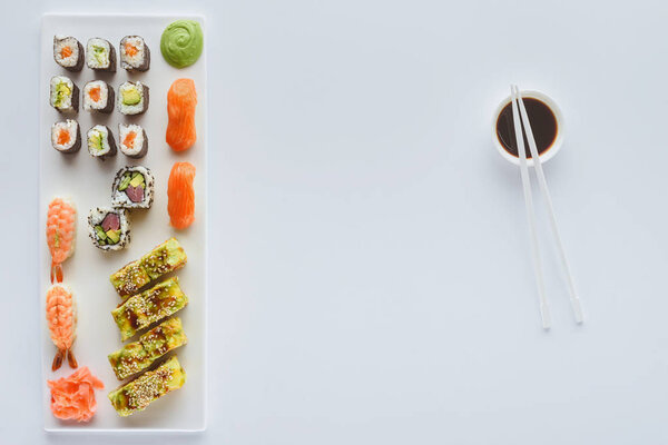 gourmet sushi set and soy sauce in bowl with chopsticks isolated on white background  