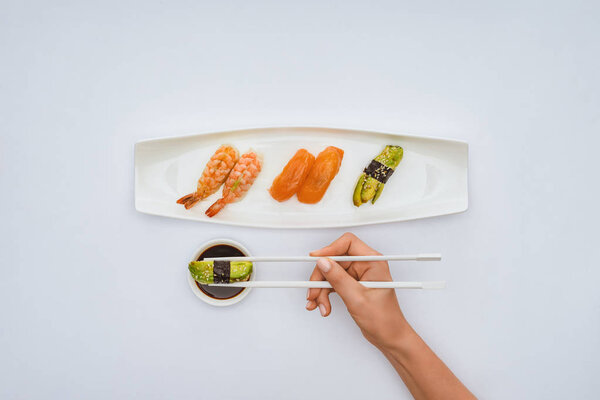 обрезанный снимок человека, держащего палочки и поедающего вкусные суши изолированные на белом
 
