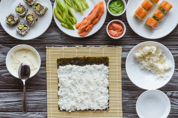 top view of rice, nori and ingredients for sushi on wooden table