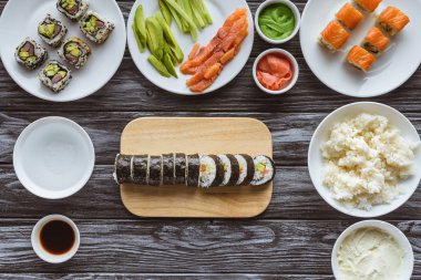 ahşap masa üzerinde lezzetli dilimlenmiş suşi roll ve maddeler üstten görünüm 