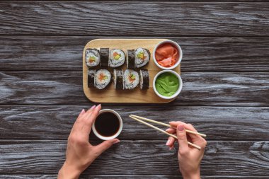 Suşi yerken chopsticks ve kase soya sosu ile tutan kişi kırpılmış atış 