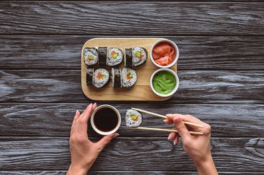 cropped shot of person holding chopsticks and eating delicious sushi roll  clipart