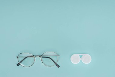 top view of eyeglasses and contact lenses container on blue background clipart
