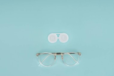 top view of eyeglasses and contact lenses container on blue background clipart