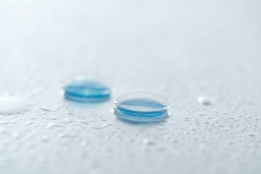 close up view of contact lenses on white background with water drops clipart