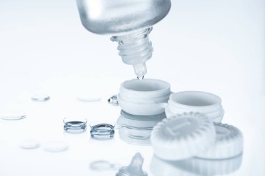 close up view of contact lenses and its storage equipment on white backdrop clipart