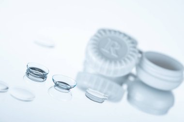 selective focus of contact lenses and container on white backdrop clipart
