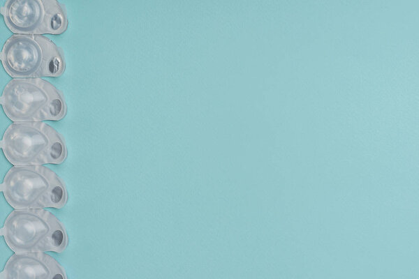 flat lay with contact lenses in white containers arranged on blue background
