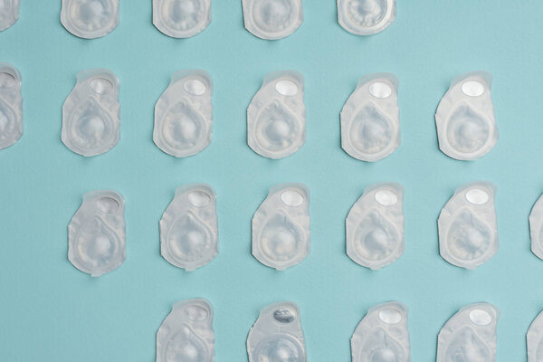 full frame of contact lenses in containers arranged on blue background