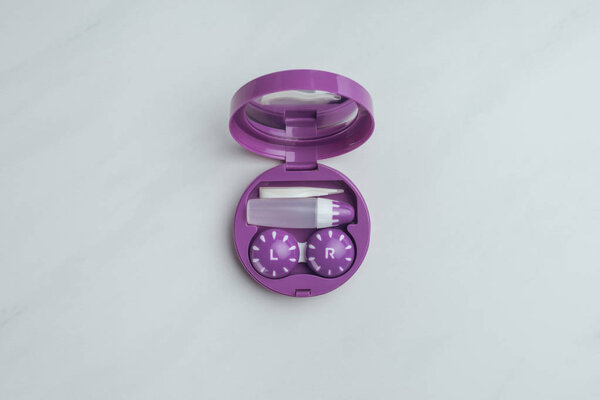 вид сверху на фиолетовый контейнер с контактными линзами и его складским оборудованием на белом столе
