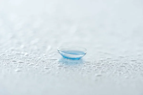close up view of contact lense on white background with water drops
