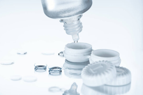 close up view of contact lenses and its storage equipment on white backdrop