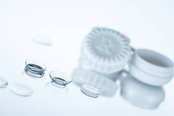 selective focus of contact lenses and container on white backdrop