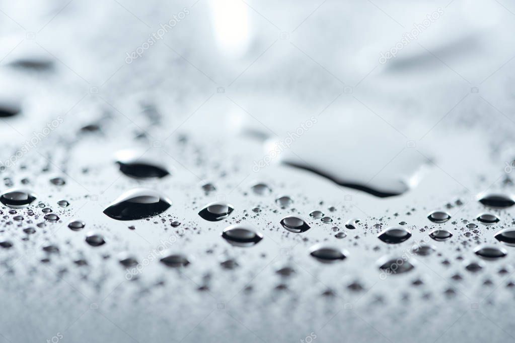 close up view of water drops on grey surface as background