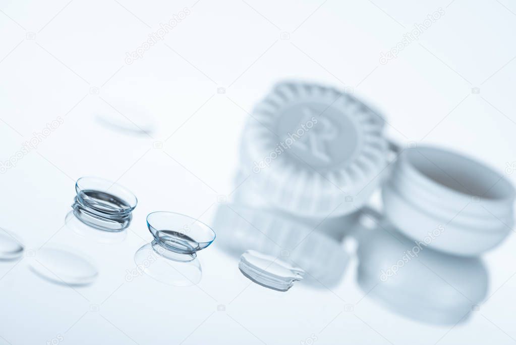selective focus of contact lenses and container on white backdrop