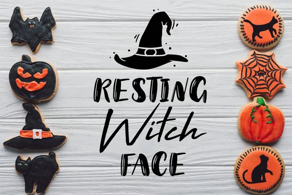 被安排的自制的万圣节曲奇饼放置在白色木质背景的行上与 休息女巫脸 字样的高视图 — 图库照片