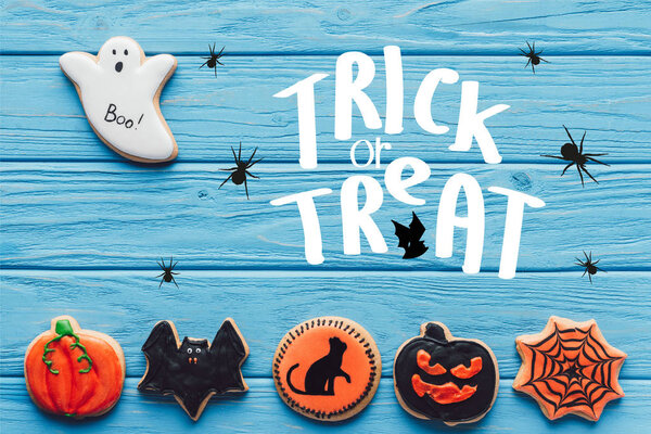 elevated view of spooky halloween cookies on blue wooden background  with "trick or treat" lettering