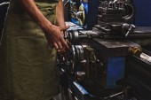 ostřižená fotografie mužského výroba pracovníka v ochranné zástěry s nástrojem stroj v továrně