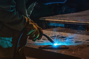 partial view of welder in protection mask welding metal with sparks at factory  clipart