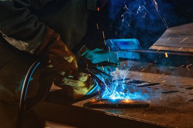 partial view of welder in protection mask brazing metal at factory  clipart