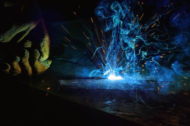 partial view of worker welding metal with sparks at factory  clipart