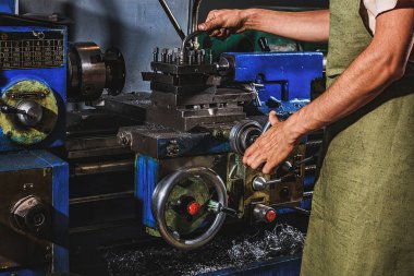 Erkek üretim işçisi koruyucu önlük fabrikasında makine aracını kullanarak kısmi görünümü