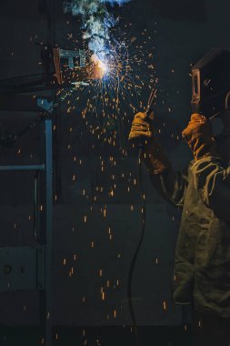 selective focus of welder in protection mask working with metal at factory  clipart