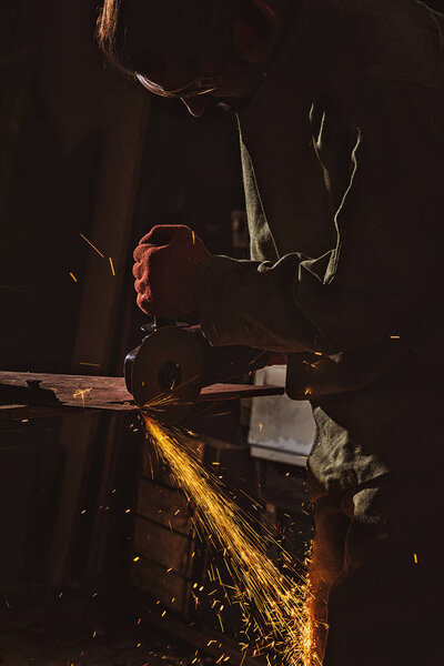male worker in protective googles working with circular saw at factory