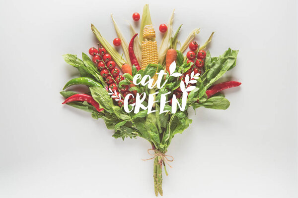 bouquet of corn cob, spinach, basil, cherry tomatoes and chili peppers isolated on white with "eat green" lettering