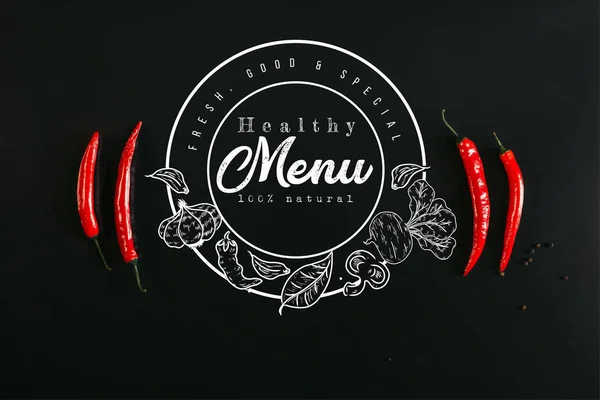 ヘルシー メニュー の文字のシールで黒い背景に赤唐辛子と胡椒のトップ ビュー — ストック写真
