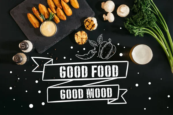 Top view of delicious baked potatoes with sauce, spices and glass of beer on black with "good food - good mood" inspiration — Stock Image Top View Delicious Baked Potatoes Sauce Spices Glass Beer Black Stock Image