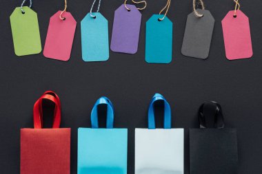 Cuma black için siyah arka plan üzerinde renkli alışveriş torbaları ve satış üstten görünüm Etiketler  