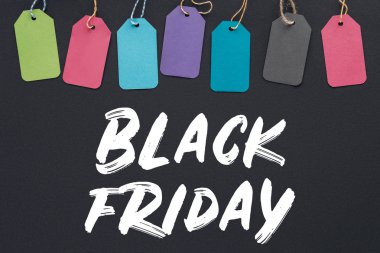 top view of colorful sale tags on black background with black friday lettering clipart