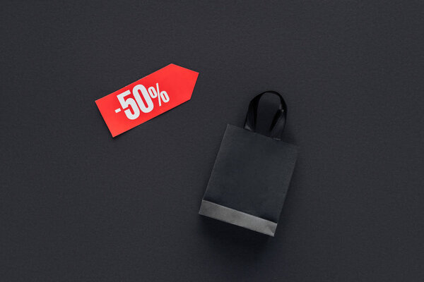 top view of shopping bag and sale tag with fifty percents discount for black friday
