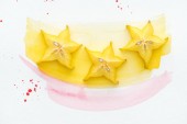top view of three ripe star fruits on white surface with yellow and pink watercolors