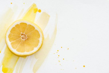 beyaz yüzeyi sarı suluboya ile kesilmiş limon parçanın üstten görünüm
