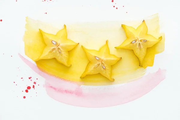 用黄色和粉红色水彩在白色表面上三成熟的星果子的上部看法 — 图库照片