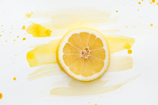 elevated view of lemon piece on white surface with yellow watercolor