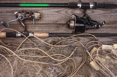top view of fishing rods and fishing net on wooden planks  clipart