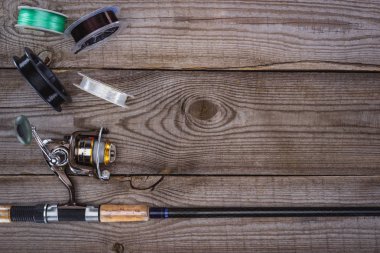 top view of various reels and fishing rod on wooden planks  clipart