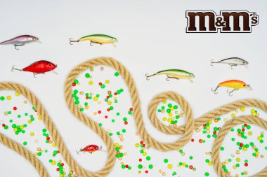 top view of fishing bait, colorful candies, nautical rope and sign m&m's isolated on white clipart