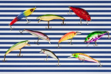 elevated view of various fishing bait on striped background  clipart