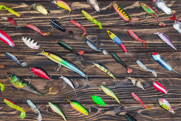 top view of arranged various fishing bait on wooden background 