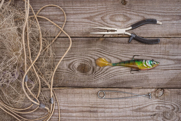 top view of fishing net, pair on nippers and fishing bait on wooden background