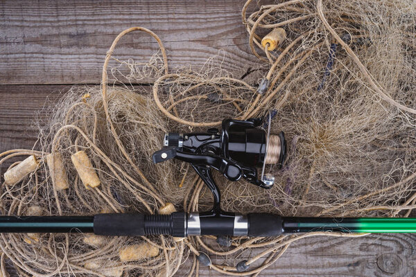 top view of fishing rod and fishing net on wooden planks 