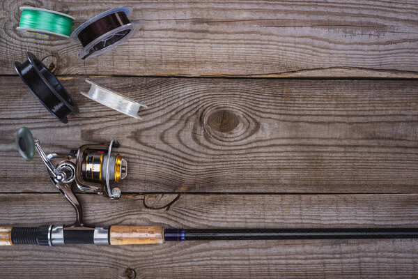 top view of various reels and fishing rod on wooden planks 