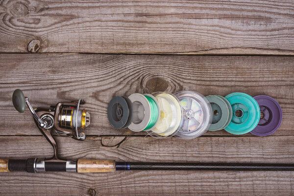 top view of fishing rod and various reels on wooden planks 
