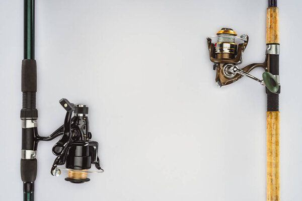 top view of two arranged fishing rods isolated on white, minimalistic concept 