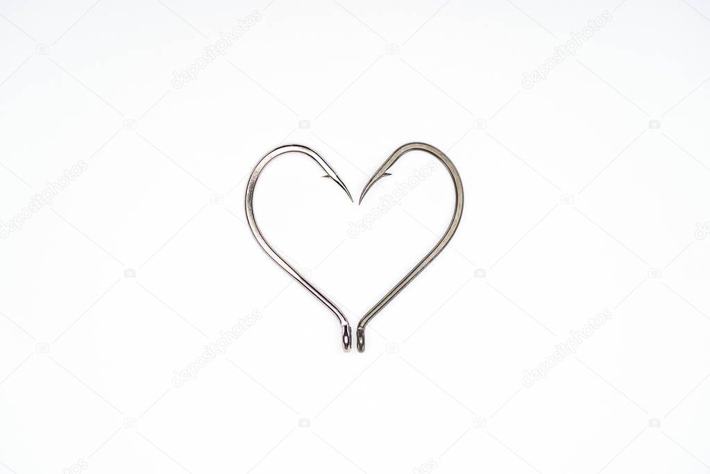 flat lay with heart symbol made of fishing hooks isolated on white